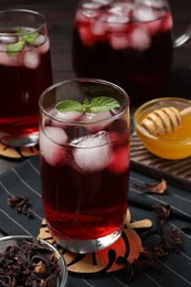 Photo of Refreshing hibiscus tea with ice cubes and mint in glass on table