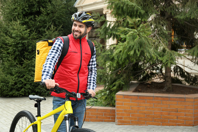Courier with thermo bag and bicycle outdoors. Food delivery service