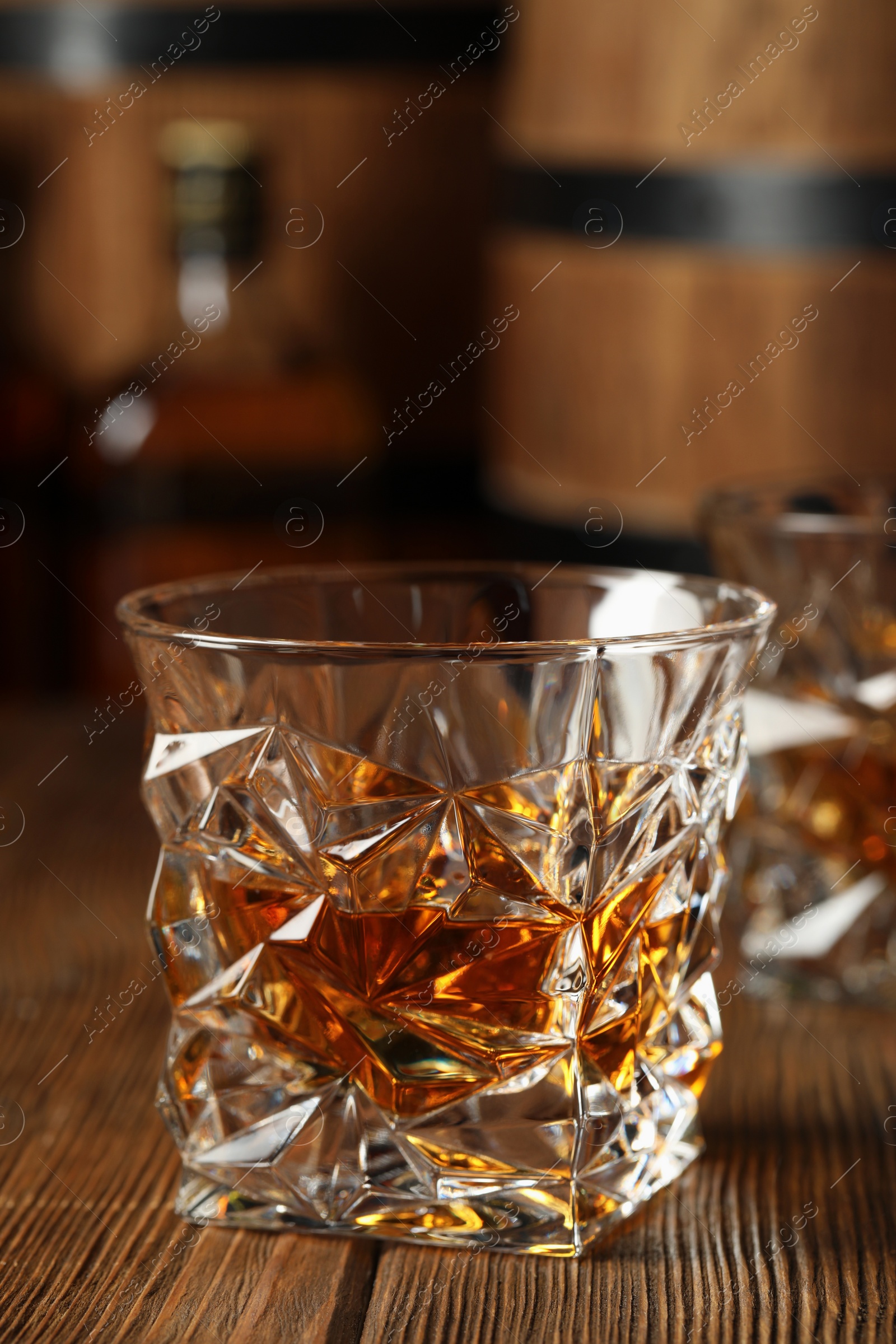 Photo of Glass of tasty whiskey on wooden table, closeup