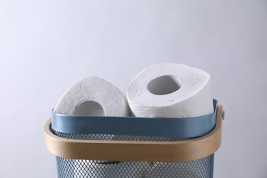 Photo of Toilet paper rolls in basket against light grey wall