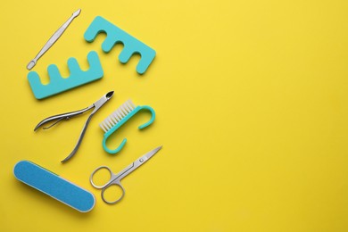 Set of pedicure tools on yellow background, flat lay. Space for text