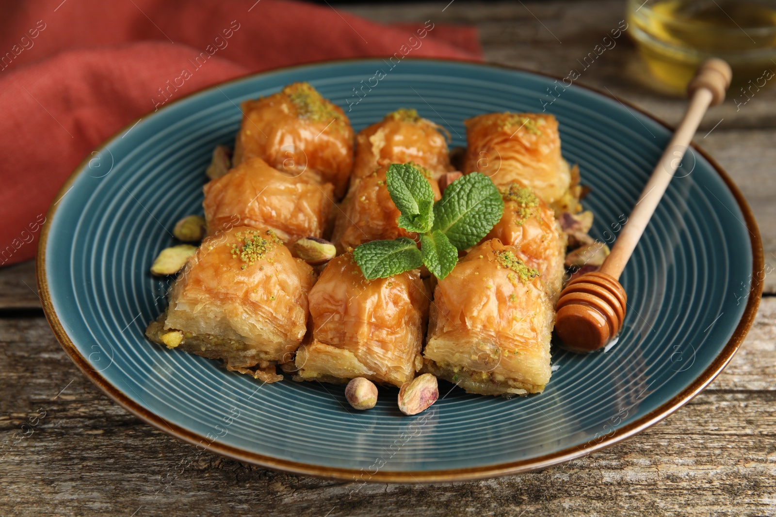 Photo of Delicious baklava with pistachios and mint on wooden table, closeup