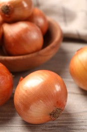 Photo of Many ripe onions on wooden table, closeup