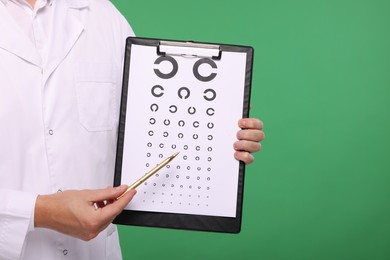 Ophthalmologist pointing at vision test chart on green background, closeup. Space for text
