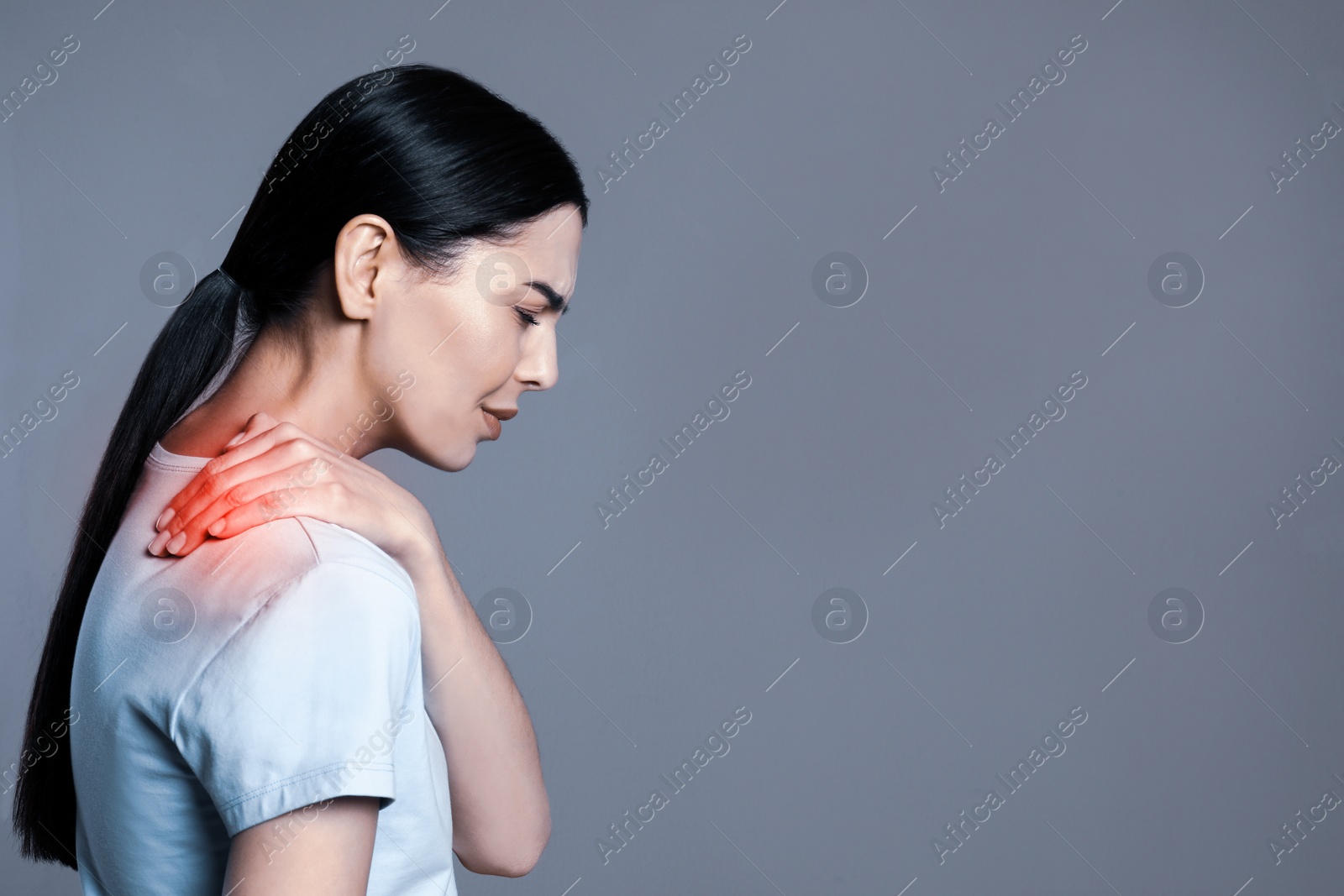 Image of Woman suffering from shoulder pain on grey background. Space for text