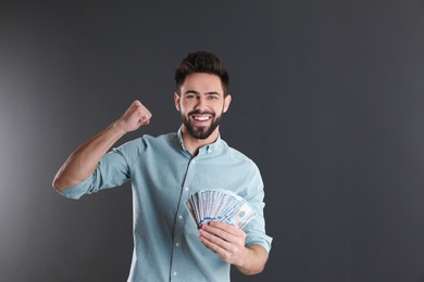 Photo of Portrait of happy young man with money on grey background. Space for text