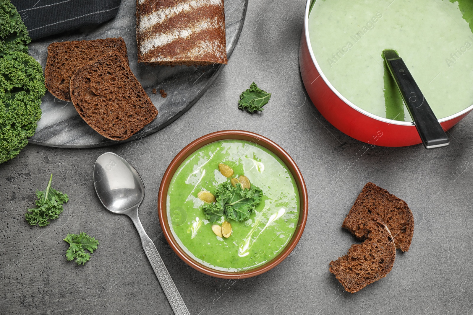 Photo of Tasty kale soup served on grey table, flat lay