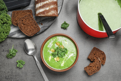 Tasty kale soup served on grey table, flat lay