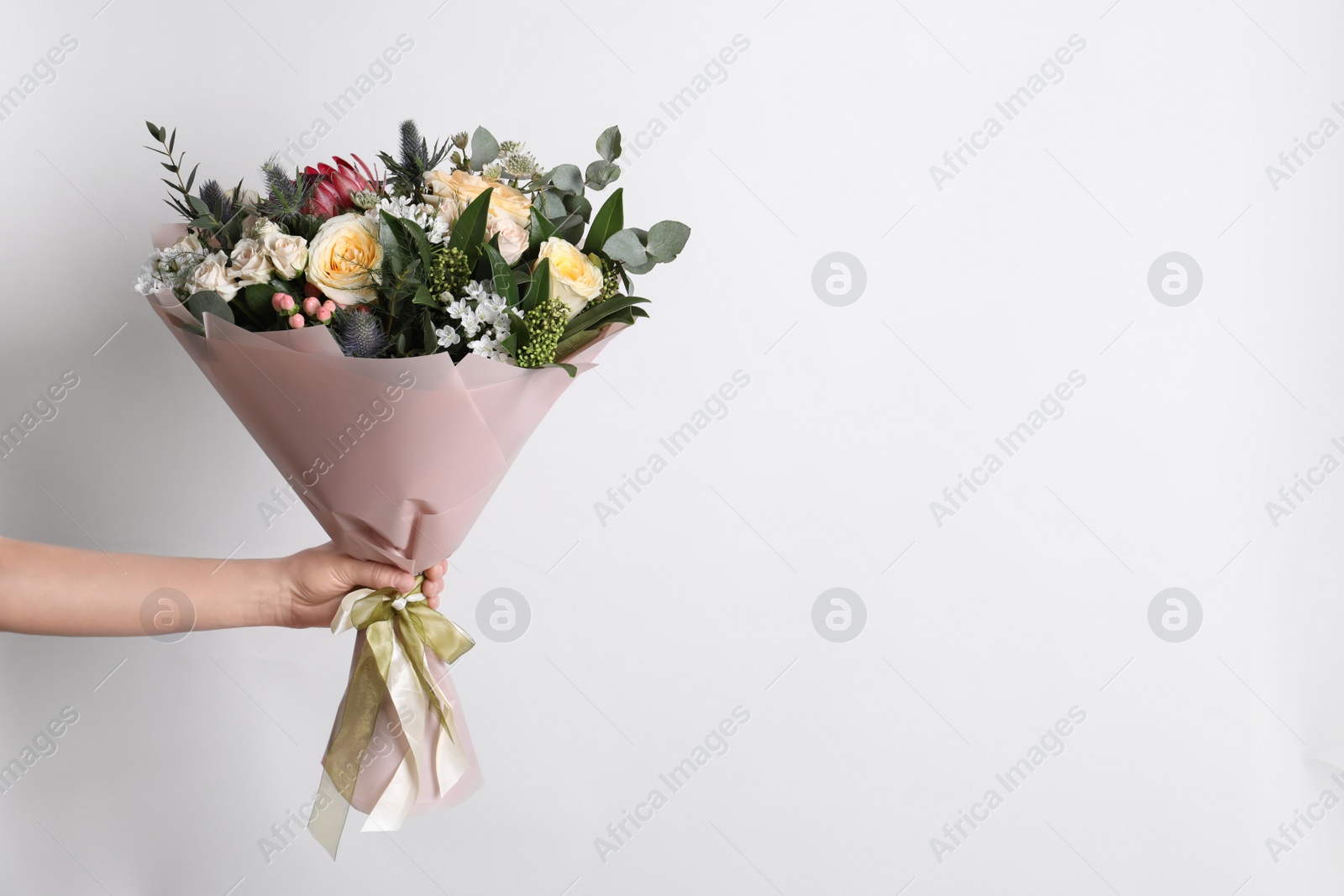 Photo of Woman holding beautiful bouquet with roses on light background, closeup. Space for text
