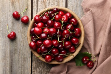 Photo of Fresh ripe cherries and towel on wooden table, flat lay