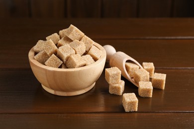 Photo of Many brown sugar cubes on wooden table