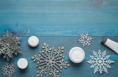 Flat lay composition with cosmetic products and snowflakes on turquoise wooden table, space for text. Winter skin care