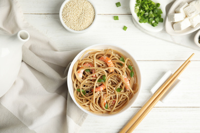 Tasty buckwheat noodles with shrimps served on white wooden table, flat lay