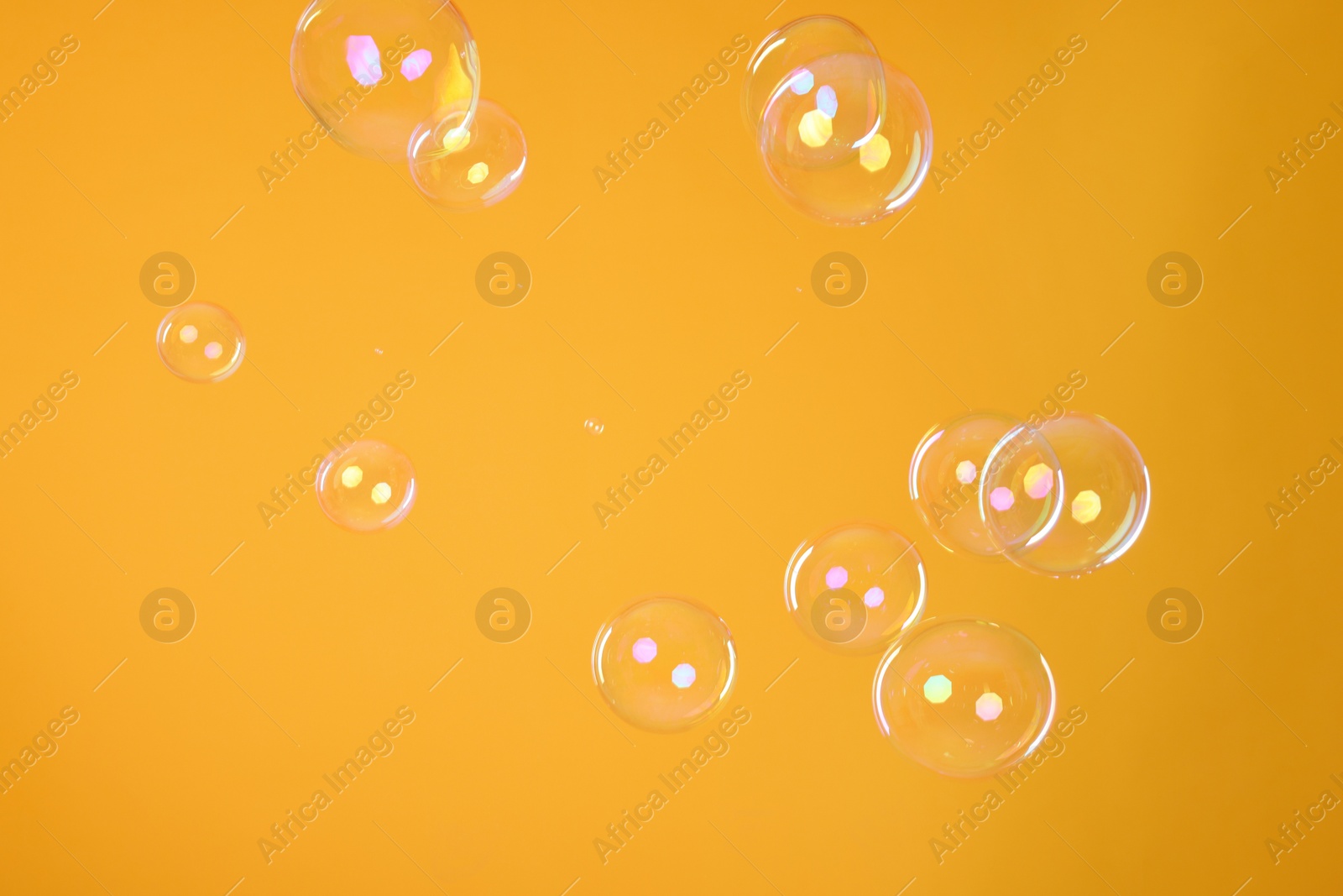 Photo of Many beautiful soap bubbles on orange background