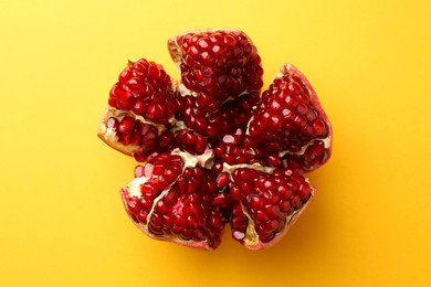 Photo of Cut fresh pomegranate on yellow background, top view