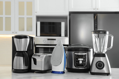 Photo of Set of modern home appliances on white marble table in kitchen