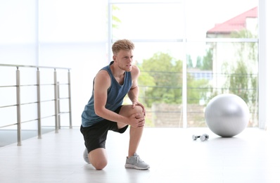Photo of Man in sportswear suffering from knee pain at gym