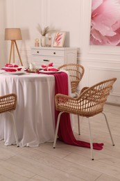 Color accent table setting. Plates, cutlery and pink napkins in dining room