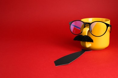 Photo of Man's face made of cup, fake mustache, glasses and paper tie on red background. Space for text