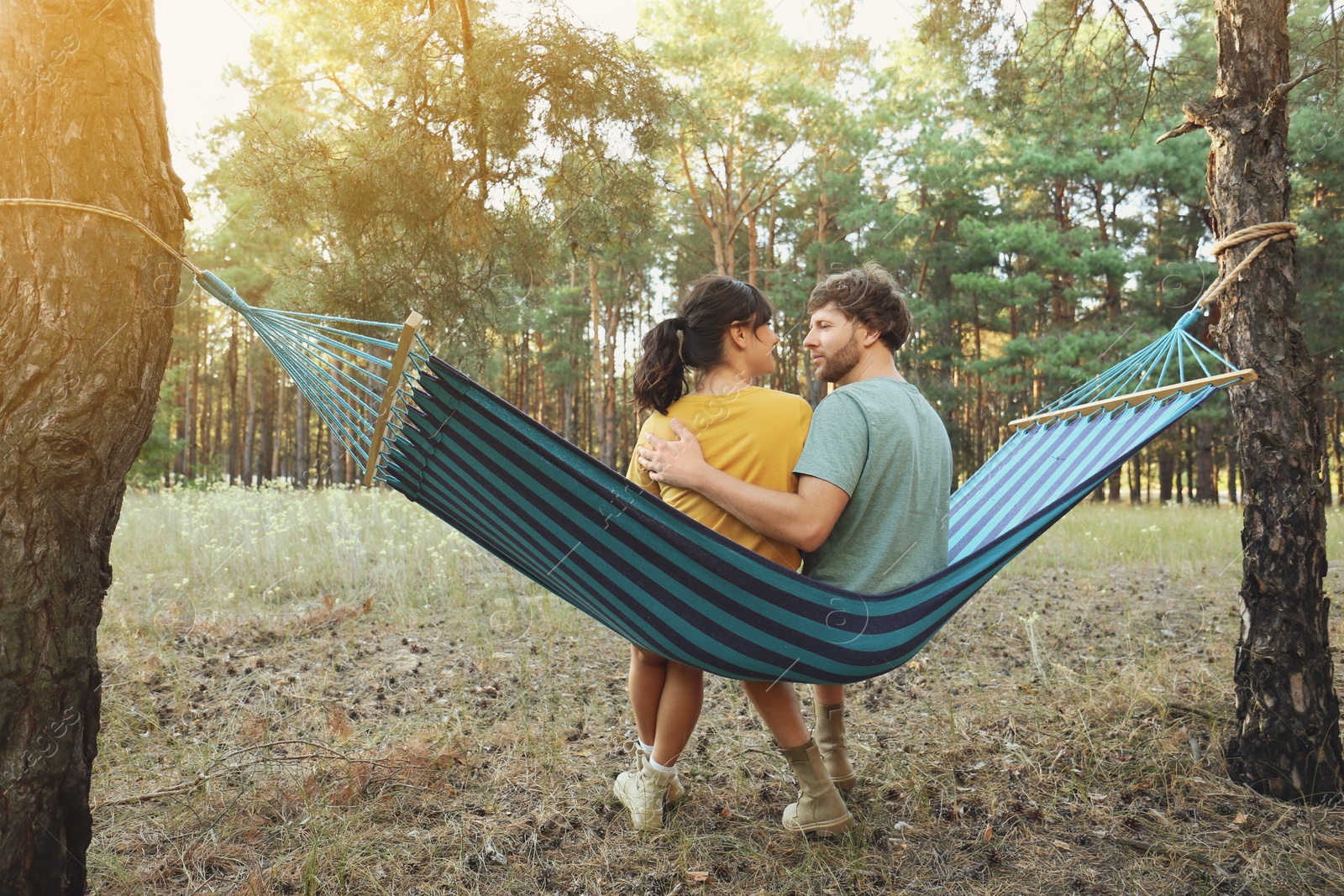 Photo of Lovely couple resting in comfortable hammock outdoors, back view