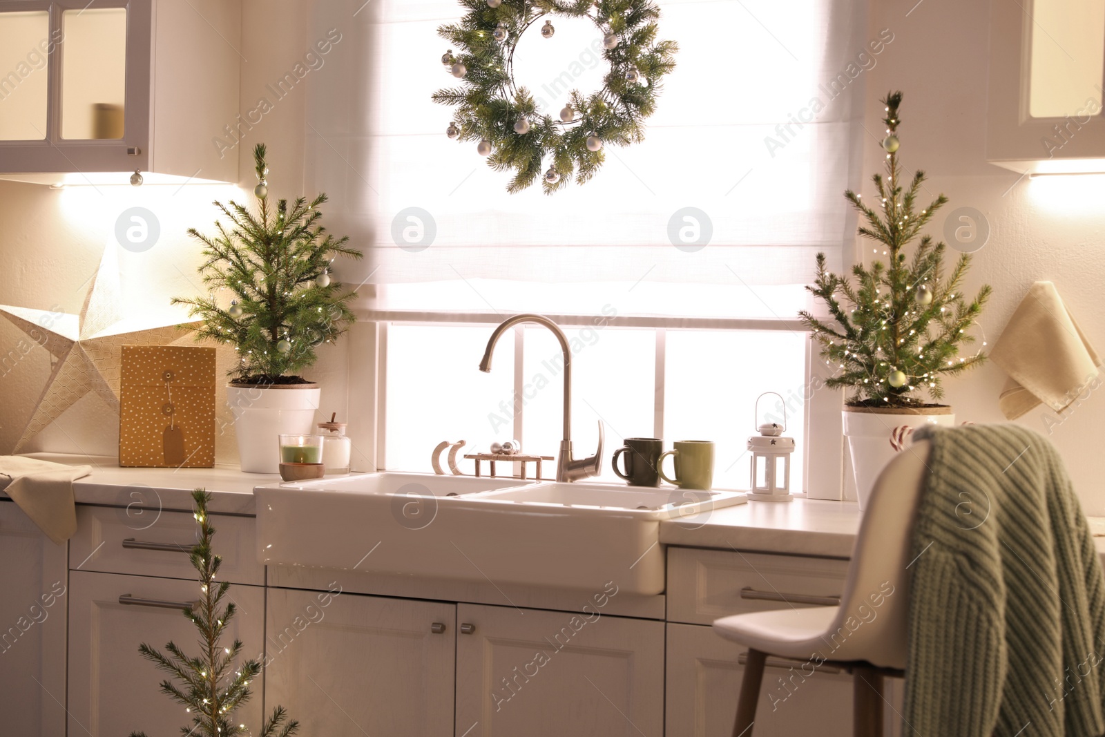 Photo of Small Christmas trees and festive decor in kitchen