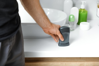 Photo of Man holding stick deodorant in bathroom, closeup view