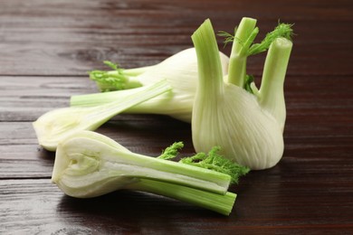 Photo of Whole and cut fennel bulbs on wooden table, closeup