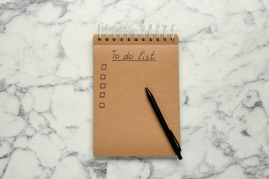 Photo of Notepad with unfilled To Do list and pen on white marble table, top view