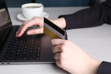 Online payment. Woman with laptop and credit card at white wooden table, closeup