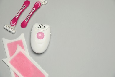Photo of Modern epilator, wax strips and razors on light grey background, flat lay. Space for text