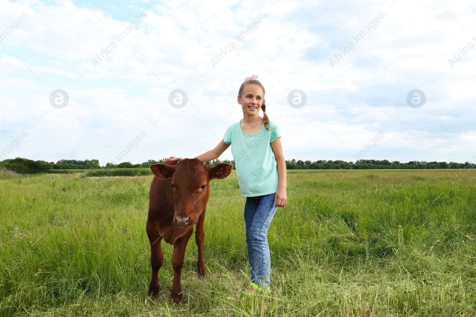 Photo of Cute little girl with calf in green field