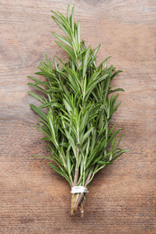 Bunch of fresh rosemary on wooden table, top view