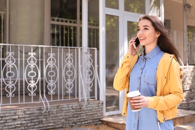 Photo of Young woman talking by phone outdoors on sunny day