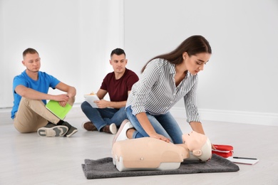 Photo of Woman practicing first aid on mannequin indoors