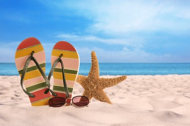 Image of Flip flops with sunglasses and starfish on sunny ocean beach, space for text. Summer vacation