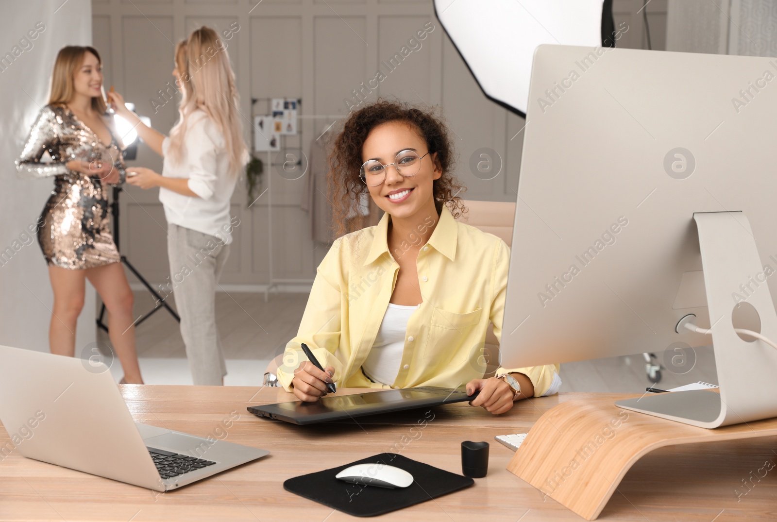 Photo of Professional African American retoucher working with graphic tablet at desk in photo studio