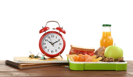Lunch box with appetizing food and alarm clock on table against white background
