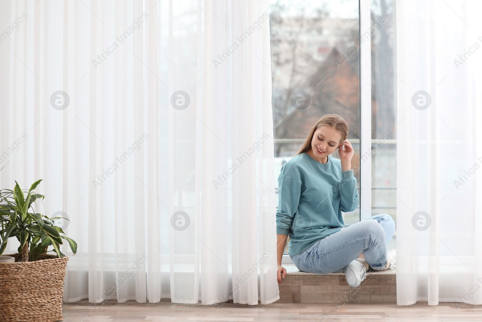 Photo of Beautiful young woman near window at home