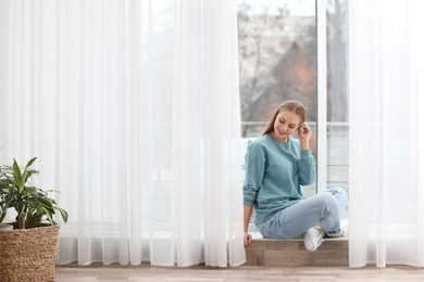 Photo of Beautiful young woman near window at home