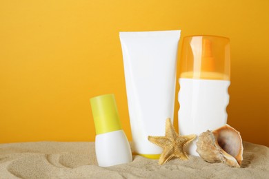 Different suntan products, seashell and starfish on sand against yellow background. Space for text