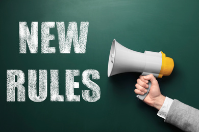 Man holding megaphone and text NEW RULES on chalkboard, closeup