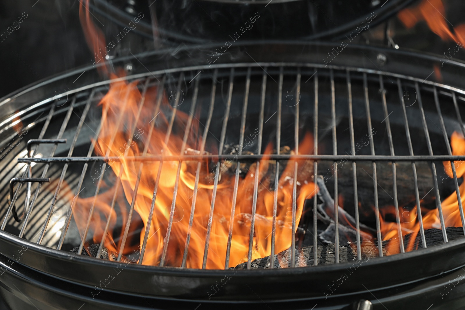 Photo of New modern barbecue grill with burning firewood, closeup