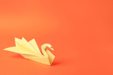 Photo of Origami art. Paper swan on orange background, space for text