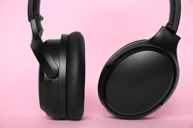 Modern wireless headphones on pink background, closeup