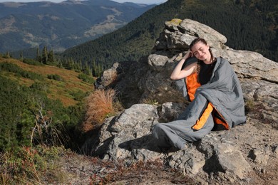 Photo of Happy tourist in sleeping bag on mountain peak