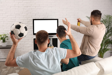 Group of friends watching football at home, back view