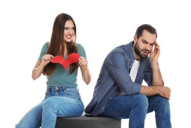 Photo of Woman tearing paper heart near her boyfriend on white background. Relationship problems