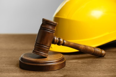 Photo of Construction and land law concepts. Gavel and hard hat on wooden table, closeup