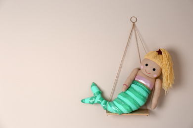 Photo of Shelf with cute toy mermaid on beige wall, space for text. Child's room interior element