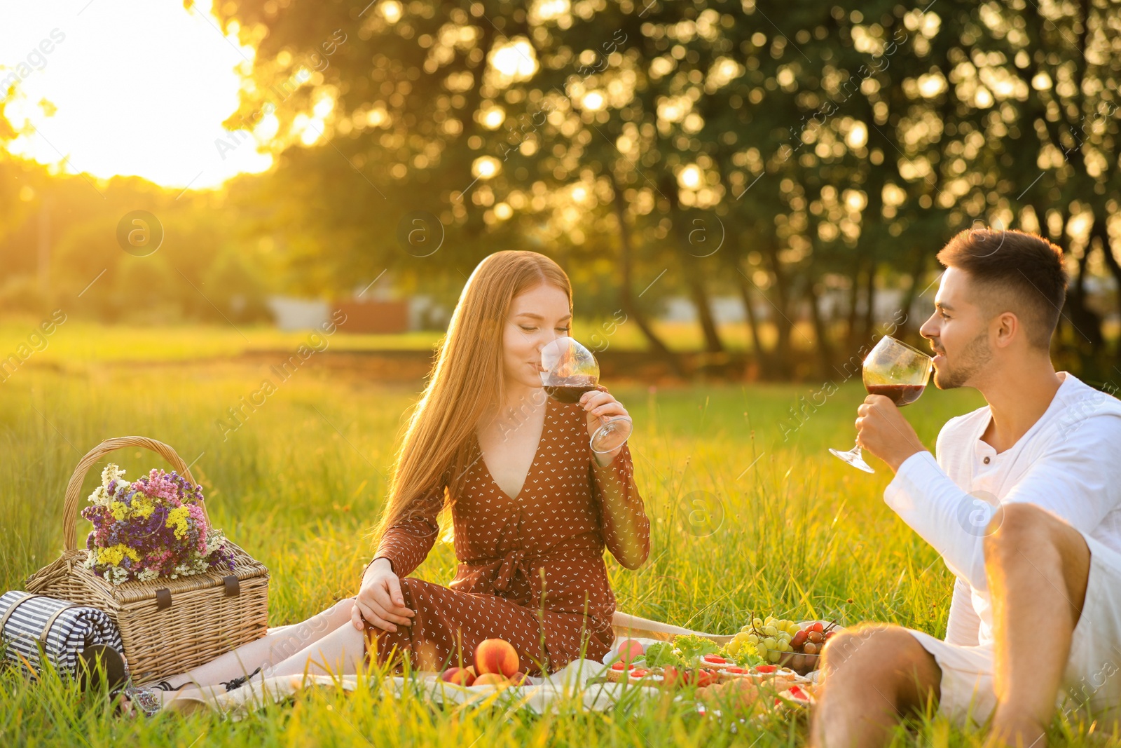 Photo of Young man and his girlfriend having picnic in green park